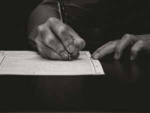 Person der udfylder juridiske dokumenter ved et skrivebord.